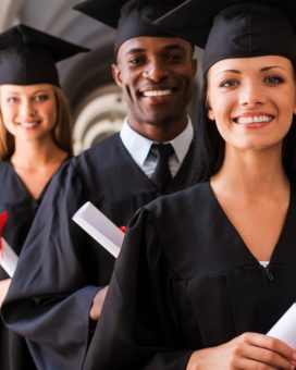 Four college graduates standing in a row and smiling